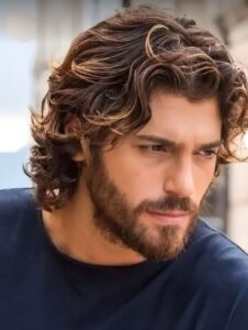 Man with a wavy shoulder-length haircut and beard, showcasing a stylish men's long hairstyle.