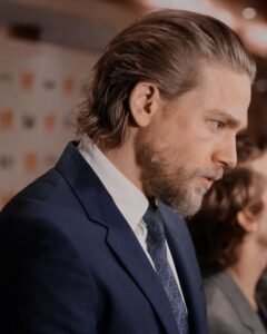 Man with slicked-back medium-long hair wearing a formal suit, showcasing a classic men's long hairstyle.